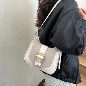Sac sous le bras rétro en toile crème et cuir avec boucle dorée porté par mannequin