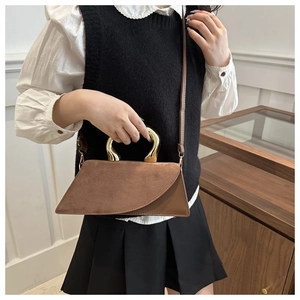 Detail of brown square crossbody bag with gold U-shaped metal handle and suede texture