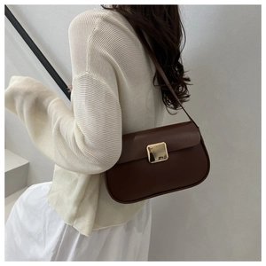 Detailed side view of a minimalist deep chocolate brown shoulder bag with a gold buckle