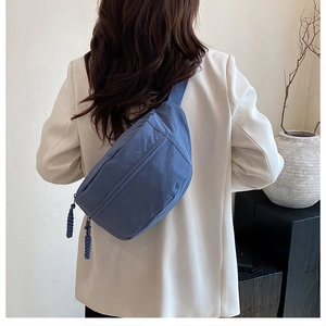 Detail of dark blue nylon crossbody bag with textured fabric and woven zipper pull