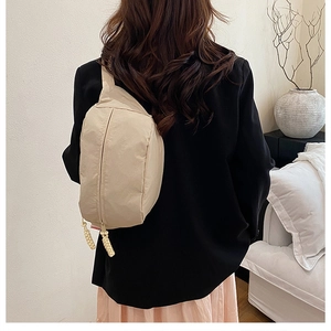 Detail of minimalist beige nylon crossbody bag with unique braided rope zipper pulls
