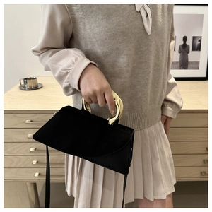Detail of elegant black square handbag with a unique liquid metal gold handle accent