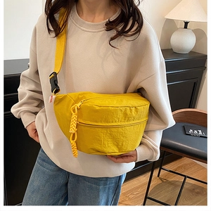 Detail of bright yellow nylon crossbody bag with adjustable strap and plastic buckle closure