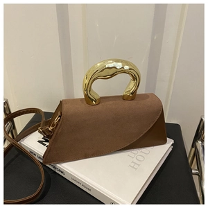 Detail of brown suede patchwork handbag with irregular wavy gold metal handle and strap