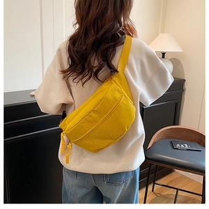 Detail of bright yellow nylon chest bag with adjustable strap and dual zipper closure