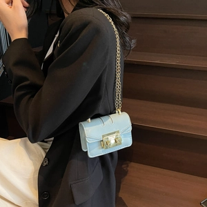 Petit sac à rabat bleu clair avec chaîne dorée porté sur un blazer noir élégant