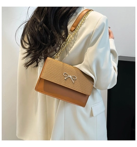 Detail of trendy patchwork woven shoulder bag with silver bow accent and chain strap
