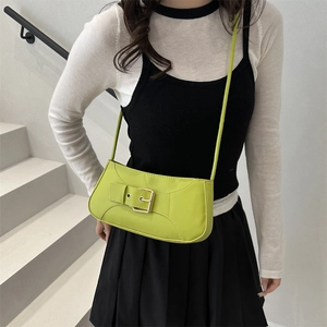 Minimalist lime green underarm bag with metal buckle strap worn by a model