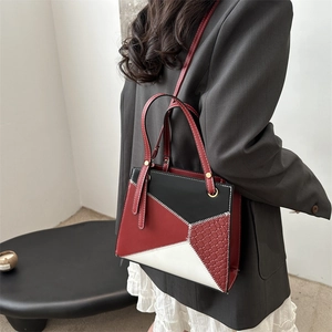 Modern color-block handbag in red, black, and white leather with a shoulder strap
