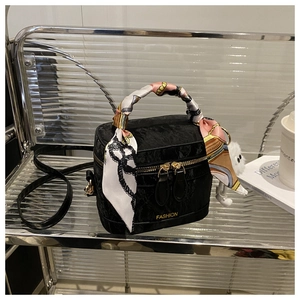 Detail van zwarte fluwelen handtas met gouden hardware en zijden sjaal aan handvat