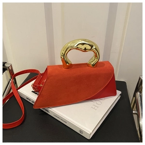 Detail view of red suede small square bag with luxury polished gold curved handle