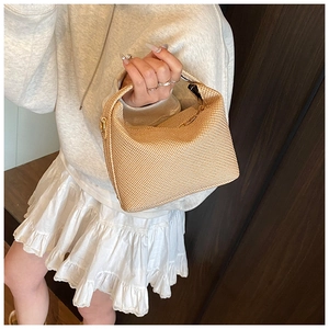 Détail d'un petit sac à main carré en paille tressée avec une fermeture éclair en métal