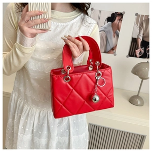 Detailed close-up of red quilted handbag featuring silver sphere charm and ring handles