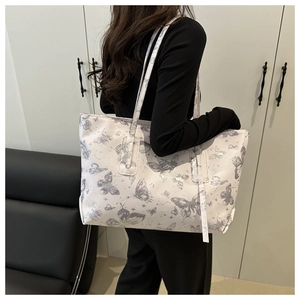 Detail of white tote bag featuring artistic butterfly prints and long shoulder straps