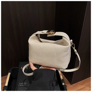 Détail du sac polochon tressé blanc avec fermoir doré et texture de tissu élégante