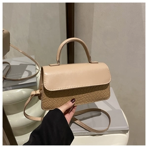 Detail of beige crossbody bag featuring textured weave pattern and golden hardware