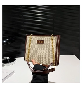 Détail du sac cabas en toile avec garniture en cuir brun et chaîne en métal doré