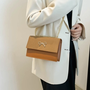 Chic brown patchwork crossbody bag with woven texture and gold bow detail on strap