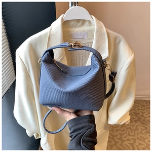 Détail d'un sac oreiller tressé bleu foncé avec fermoir rotatif doré et poignée