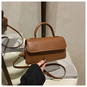 Detail of caramel brown crossbody bag featuring mixed smooth and woven leather textures