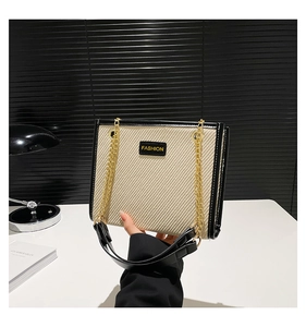 Détail du sac bandoulière contrasté avec texture tissée, chaîne et étiquette tendance