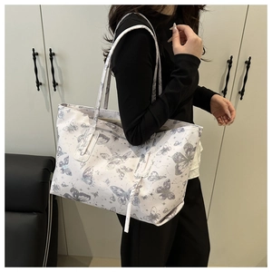 Detail of white butterfly print tote bag with star patterns shown on model shoulder