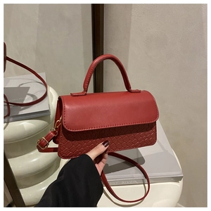 Detail of red leather handbag with woven texture, top handle, and golden hardware hooks