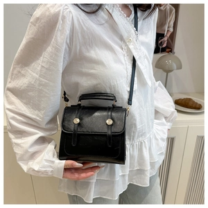 Détail d'un petit sac à bandoulière noir vintage avec boucles dorées et fini mat