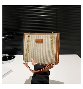 Détail du sac cabas en toile bicolore avec bordure en cuir marron et chaîne dorée