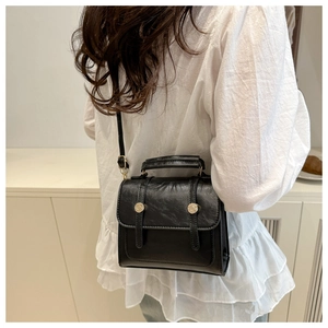 Détail du sac bandoulière vintage noir avec texture plissée et boucle argentée sur modèle