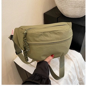 Detail of olive green nylon chest bag with woven zipper pulls and fashion label