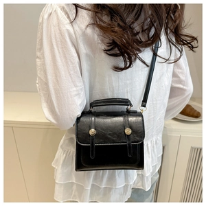 Détail d'un sac bandoulière vintage noir avec garniture dorée porté par un mannequin