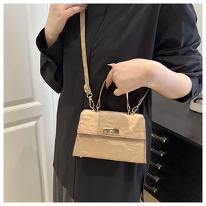 Detail of light khaki pleated leather handbag with golden rotating lock and strap