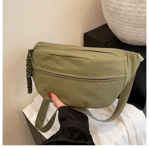 Detailed shot of olive green nylon crossbody bag with woven zipper puller texture