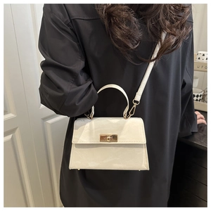 Detail of a creamy marble pattern handbag with a golden rotating lock and top handle
