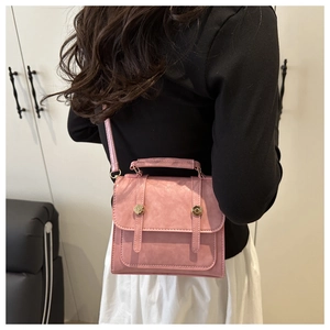 Détails d'un sac à bandoulière rose avec sangle réglable et ornements métalliques