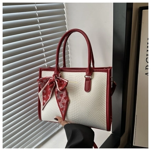 Close-up of red and white snakeskin embossed bag with heart patterned silk scarf bow