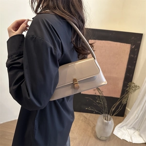 Sac sous le bras beige vintage français avec boucle dorée porté par un mannequin chic