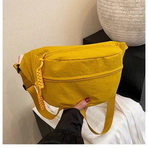 Detail of yellow nylon crossbody bag with chunky braided zipper pull and fashion label