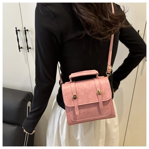 Détail du sac à bandoulière vintage rose avec boucles dorées et doubles sangles décoratives