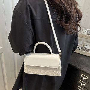 White minimalist crossbody square bag with crocodile texture and top handle shown on model