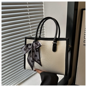 Detail of snake pattern tote bag with black trim and elegant heart print silk scarf handle