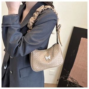 Détail du sac beige tissé avec papillon argenté et bandoulière à volants chic