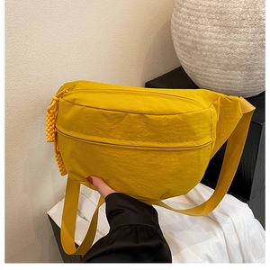 Detail of bright yellow nylon crossbody bag with waterproof texture and wide strap