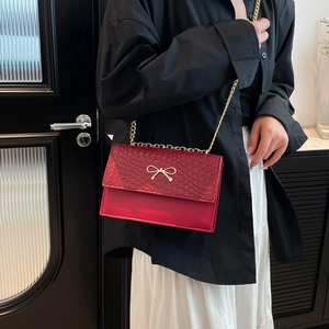 Chic red crossbody chain bag with snake skin texture and gold bow buckle decoration