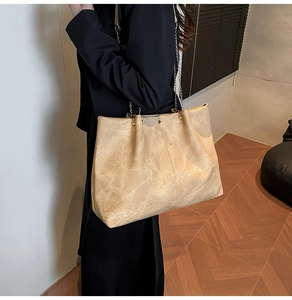 Close-up of vintage texture large tote bag with gold chain strap and rivet details