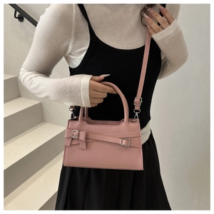 Close-up of pink square handbag featuring decorative bow and silver metal hardware details