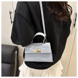 Detail of light blue crossbody bag with pleated texture and gold metal turn-lock closure