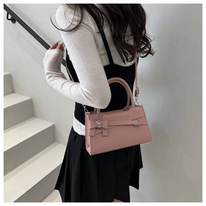 Pink minimalist crossbody square bag with silver metal bow clasp shown on a model