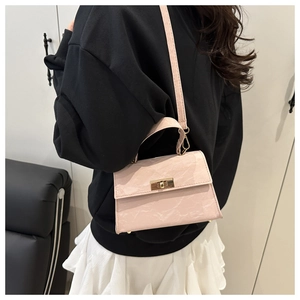 Detail of pink crossbody bag with marble texture and golden square twist lock on a shoulder